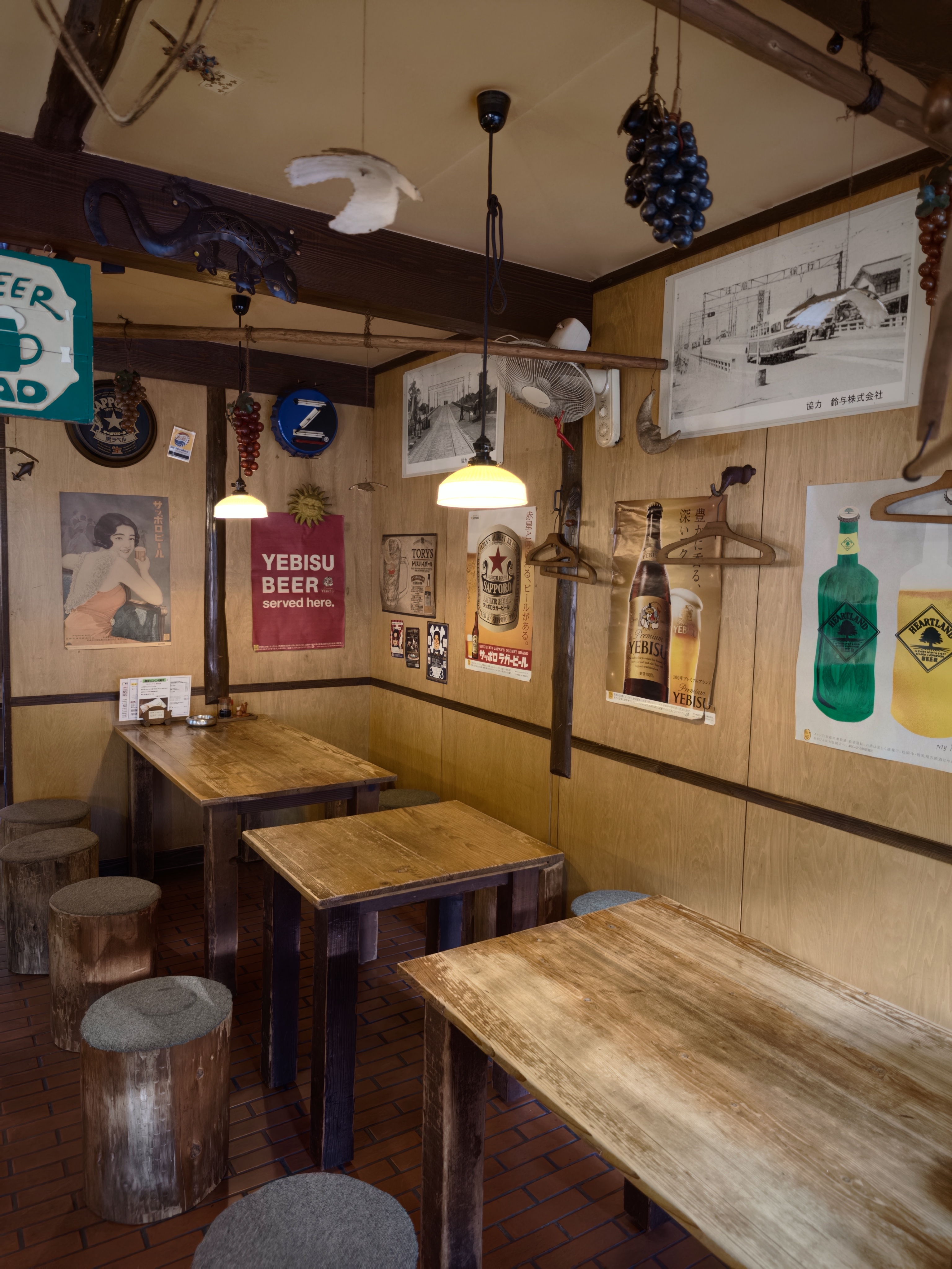 やしまの店内。丸太の椅子と木のテーブル、壁一面のレトロなビールのポスター